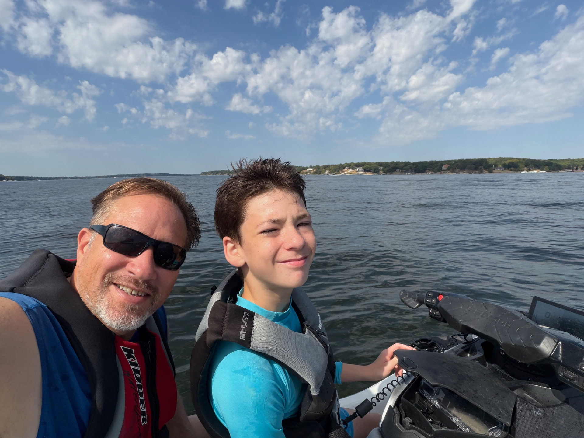Ryan and Isaac smiling on the water wearing life jackets